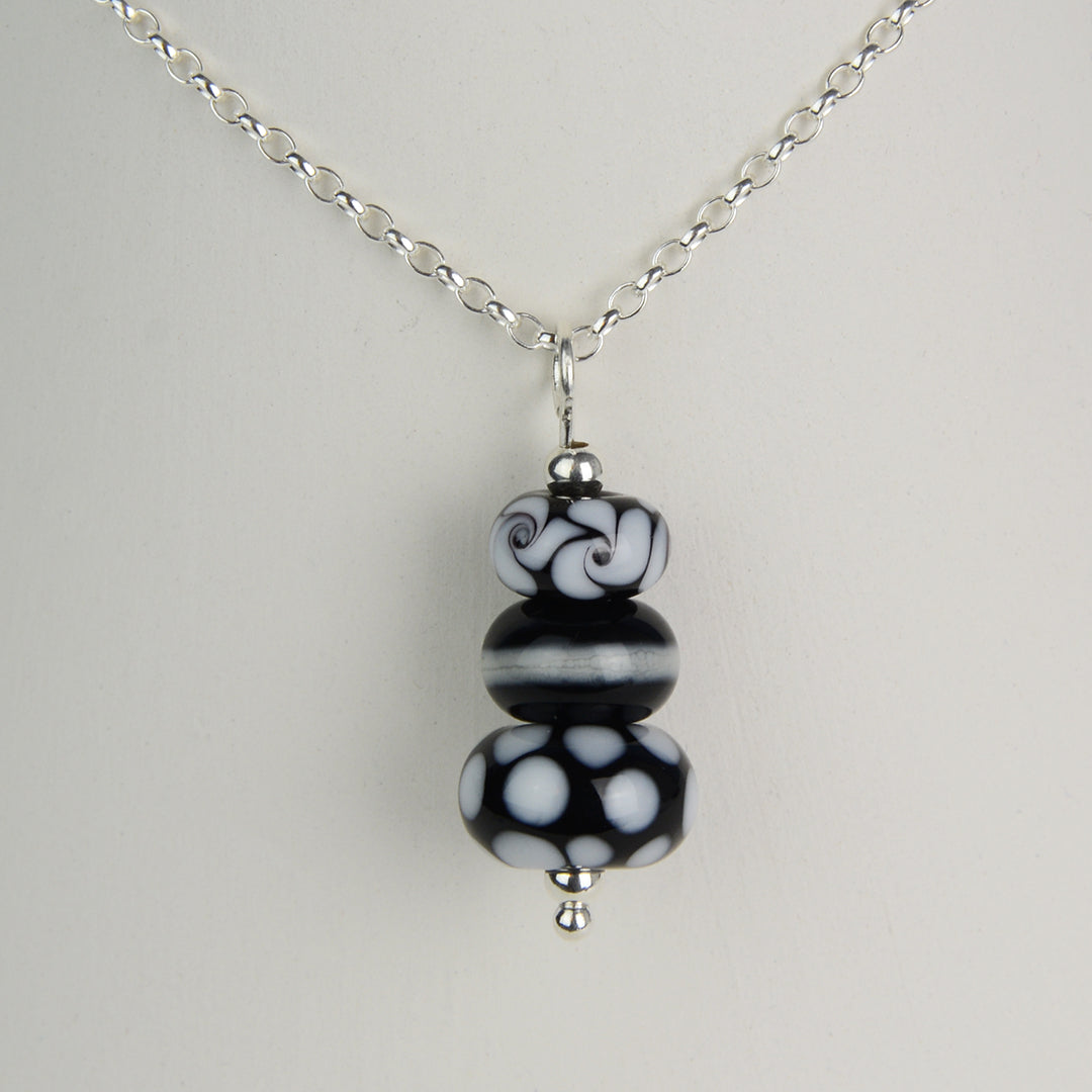 Three black and white glass beads making a pendant on silver chain