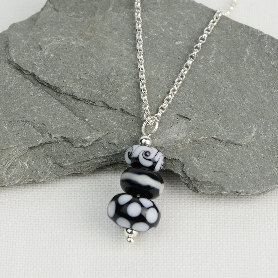 Three black and white glass beads making a pendant on silver chain