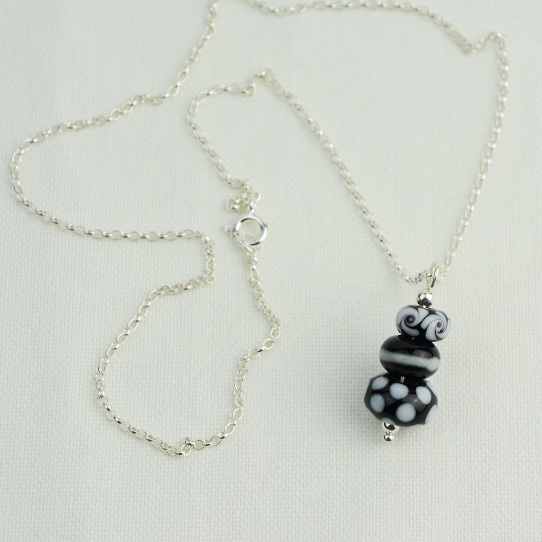 Three black and white glass beads making a pendant on silver chain