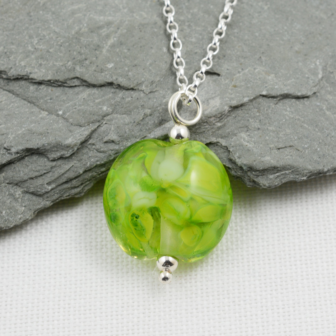 Shades of green lentil shaped glass bead pendant on silver chain