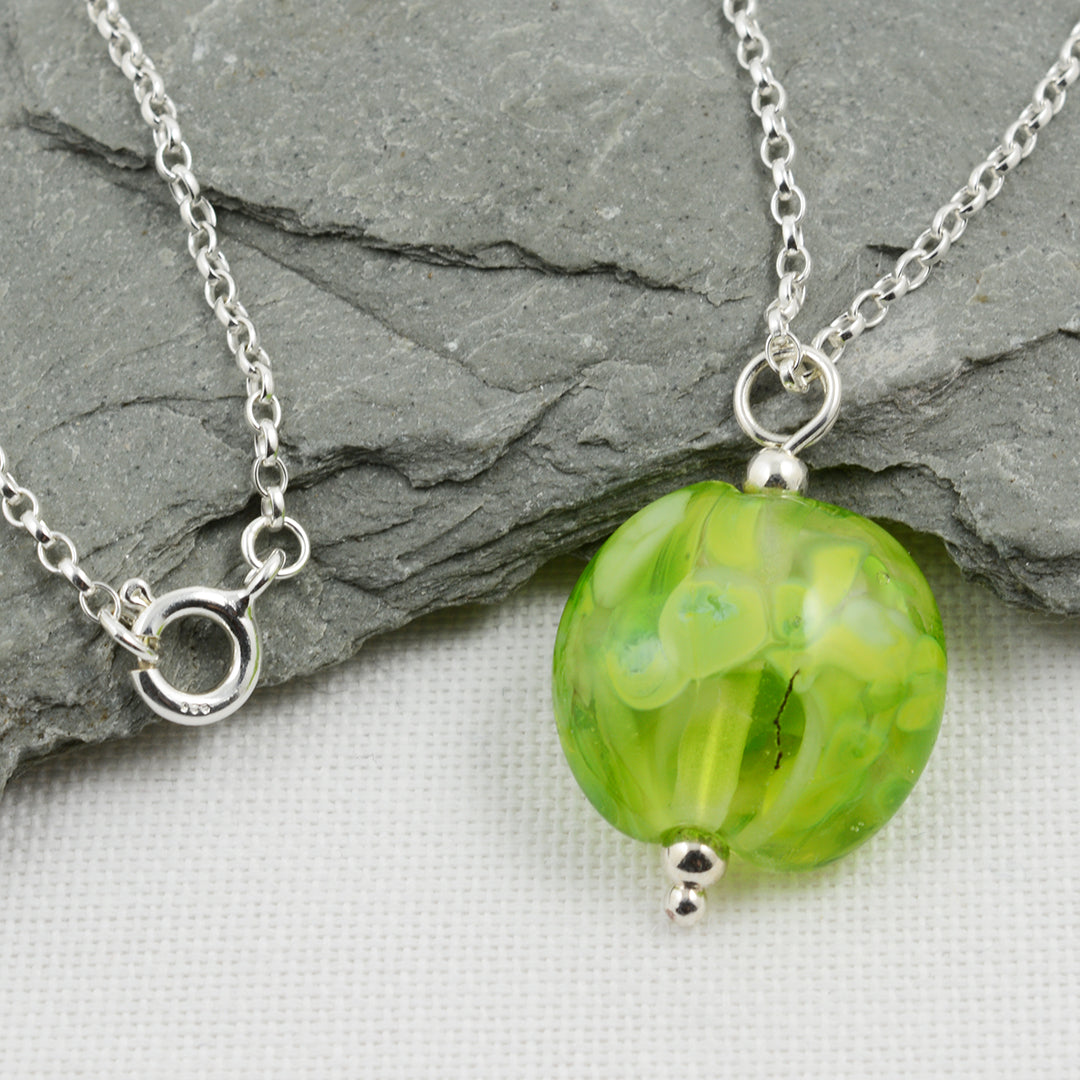 Shades of green lentil shaped glass bead pendant on silver chain