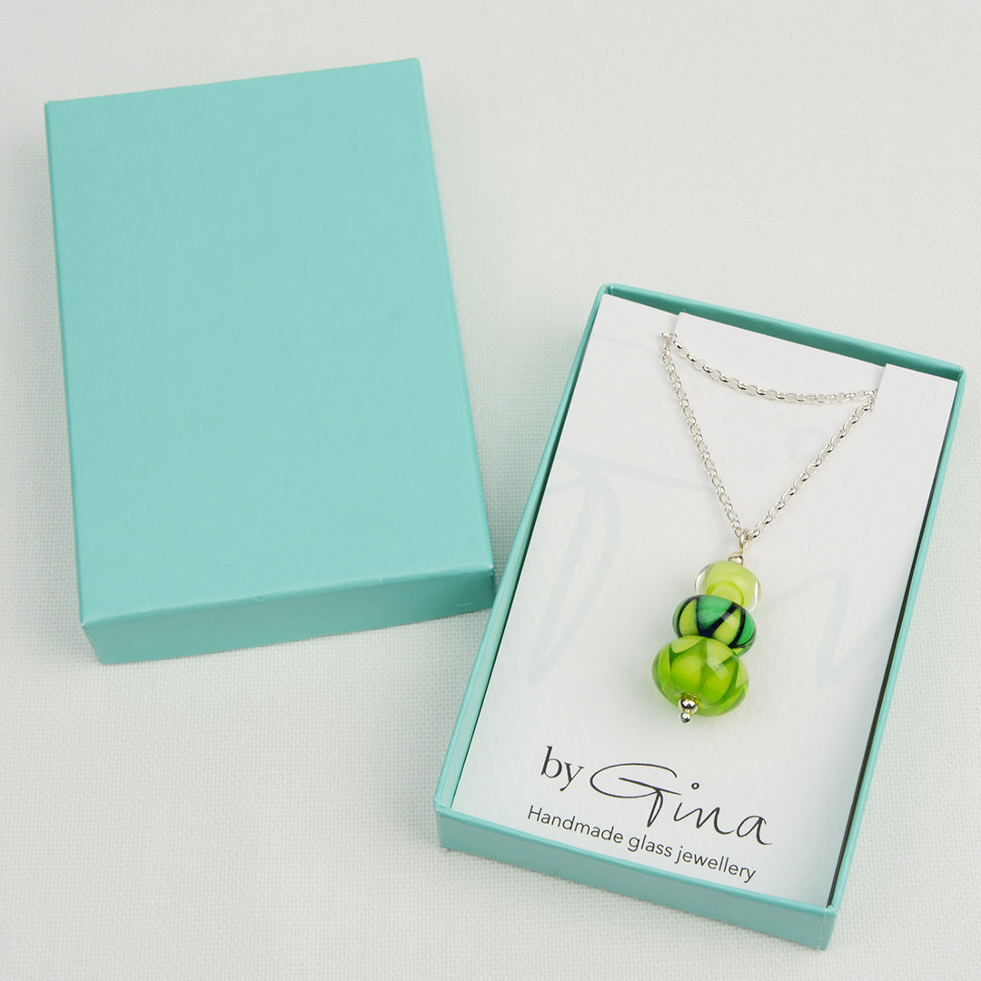 Two green glass beads and one green and blue bead making a pendant on silver chain in turquoise gift box