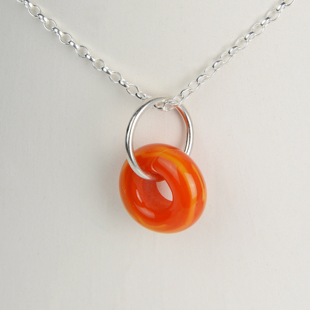 Orange glass doughnut shaped bead pendant on silver chain