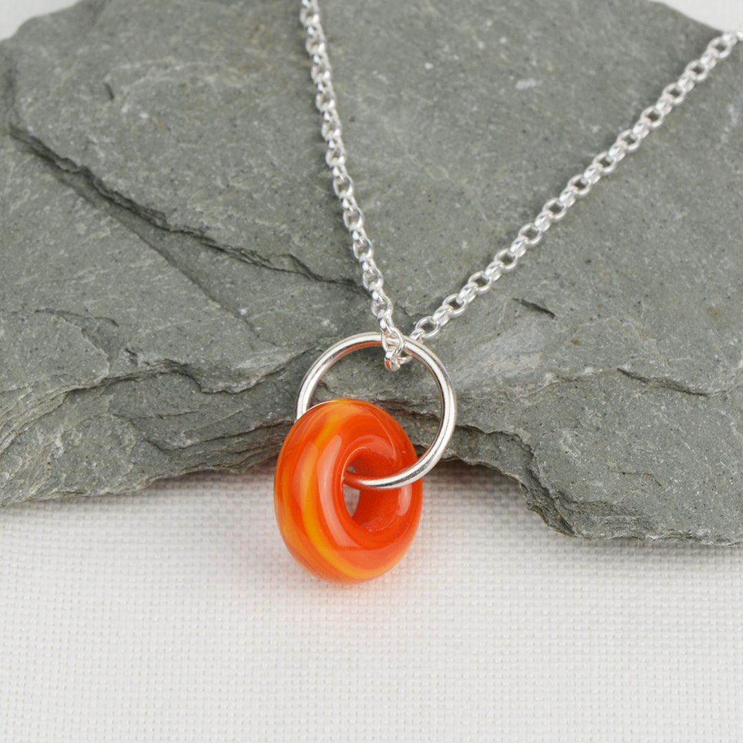 Orange glass doughnut shaped bead pendant on silver chain