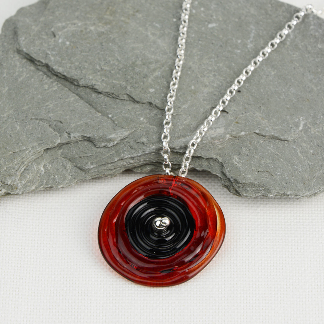 Spiral of red and black glass to replicate a poppy flower on a silver chain