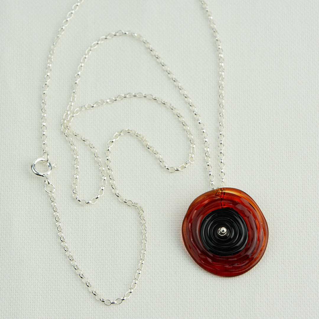 Spiral of red and black glass to replicate a poppy flower on a silver chain