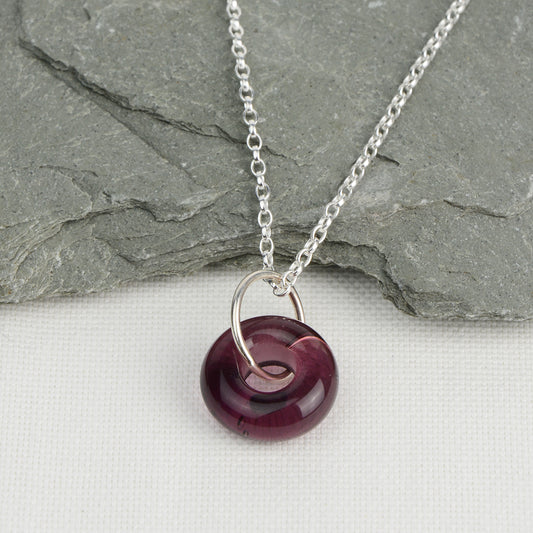 Doughnut shaped plum coloured glass bead on silver chain