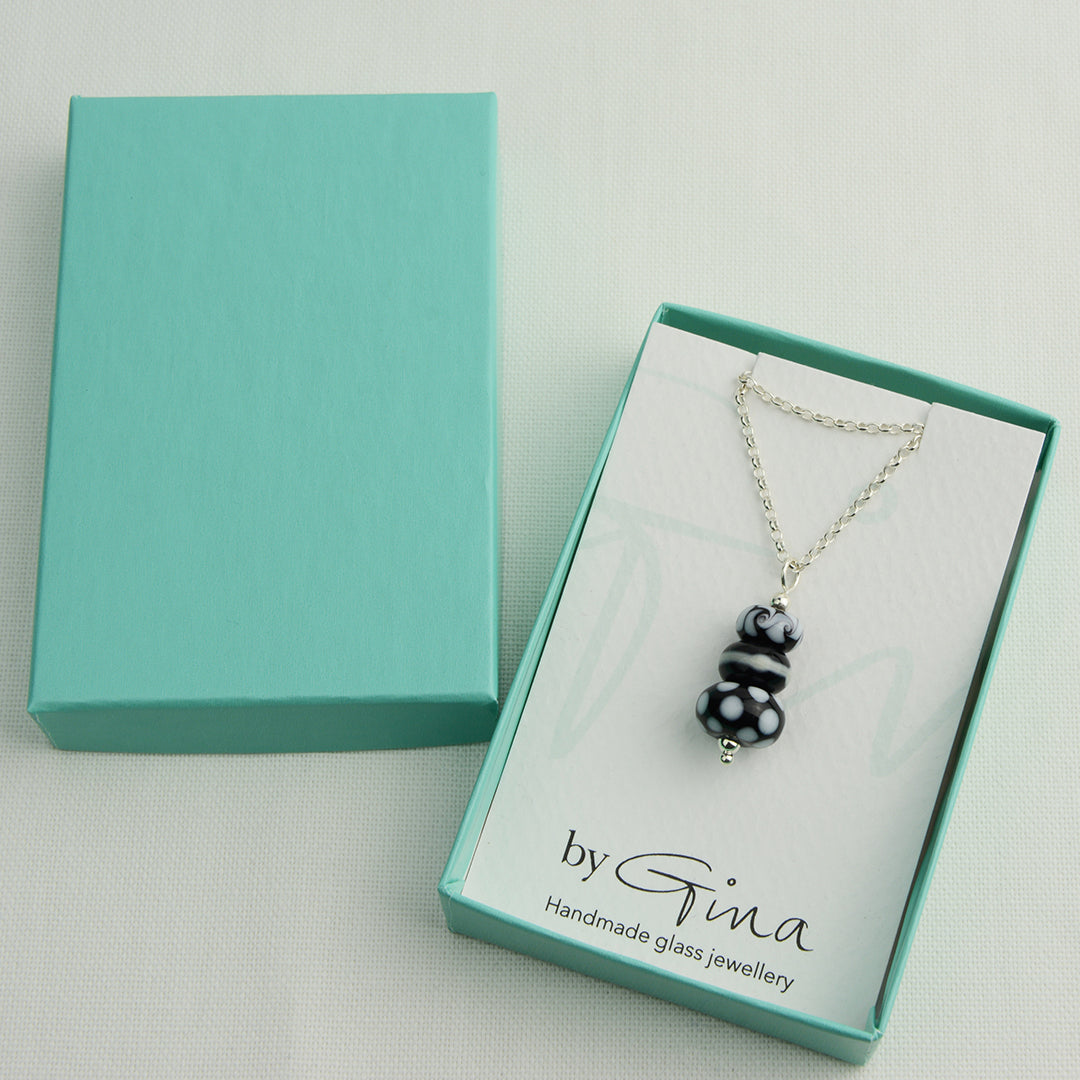 Three black and white glass beads making a pendant on silver chain in turquoise gift box