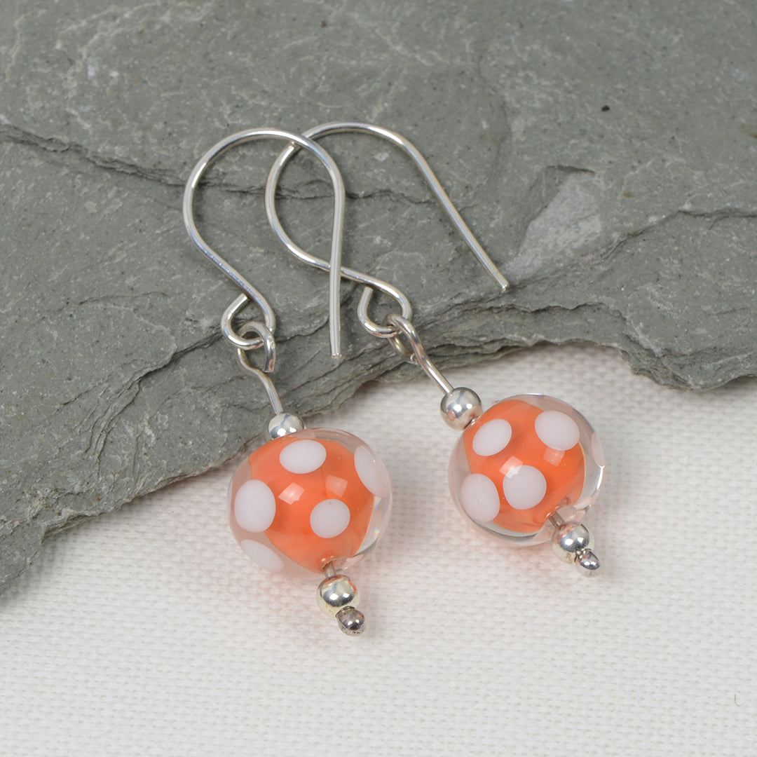 Encased orange and white spotty glass bead earrings