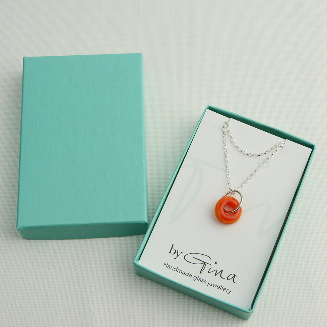 Orange glass doughnut shaped bead pendant on silver chain in turquoise gift box