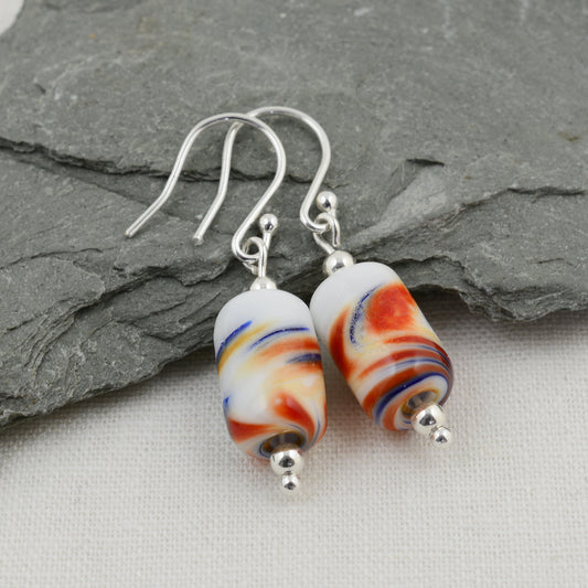 Long drop silver earrings with barrel shaped white glass beads with red and blue swirls