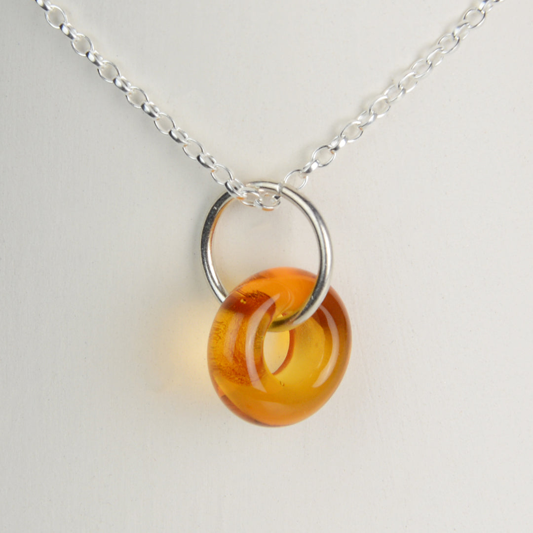 Doughnut shaped amber glass bead on silver chain