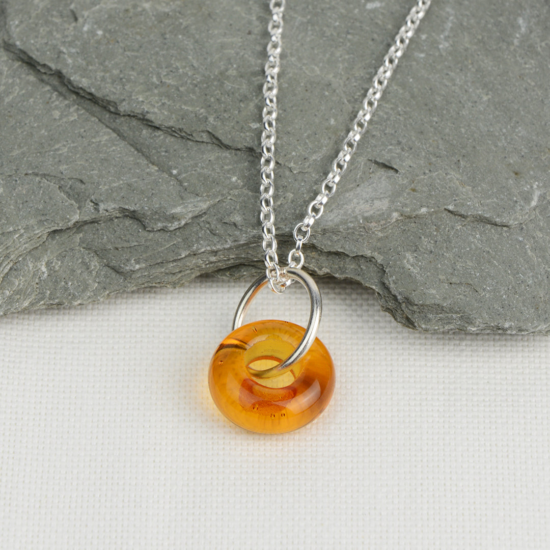 Doughnut shaped amber glass bead on silver chain