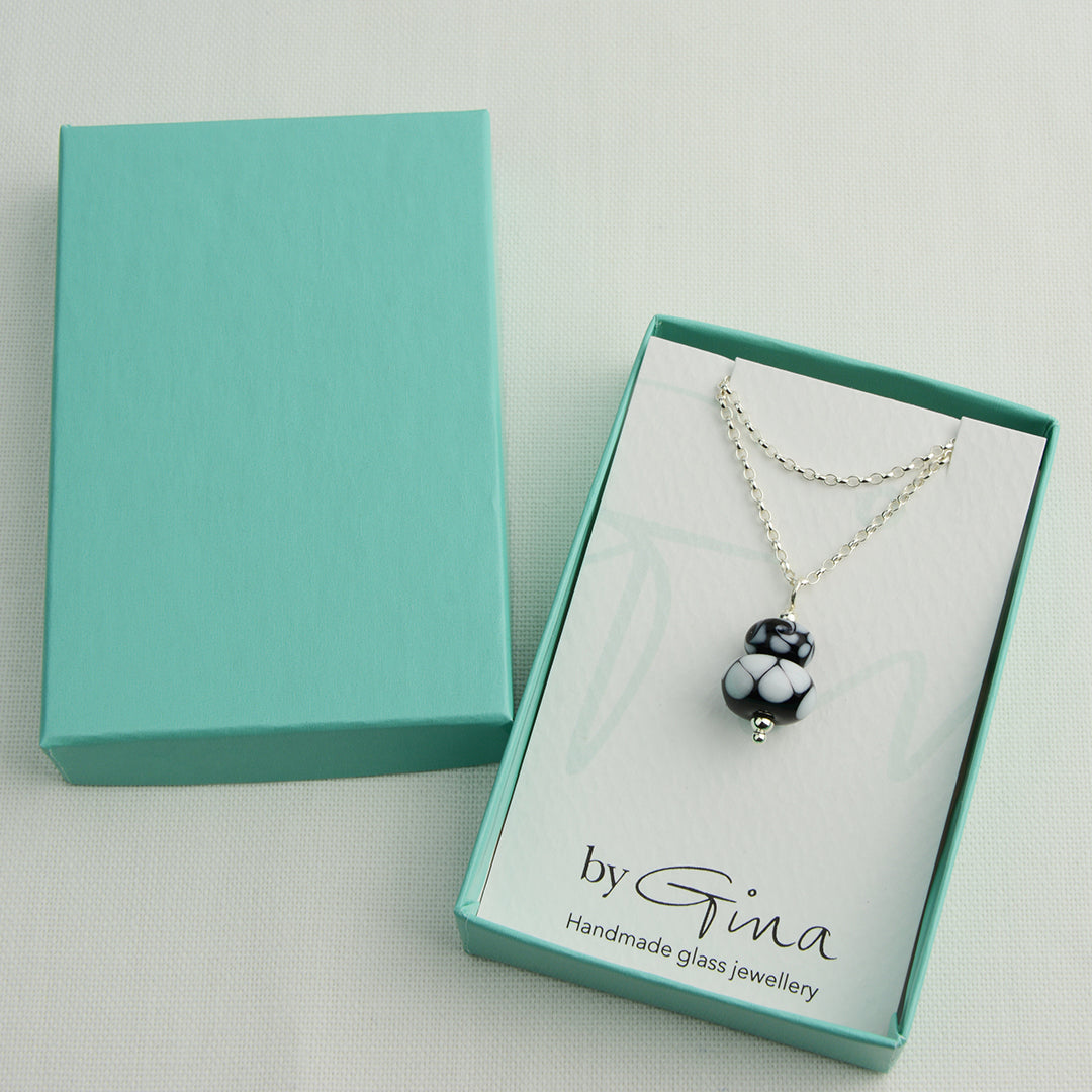 Two black and white glass beads making a pendant on silver chain in a turquoise gift box