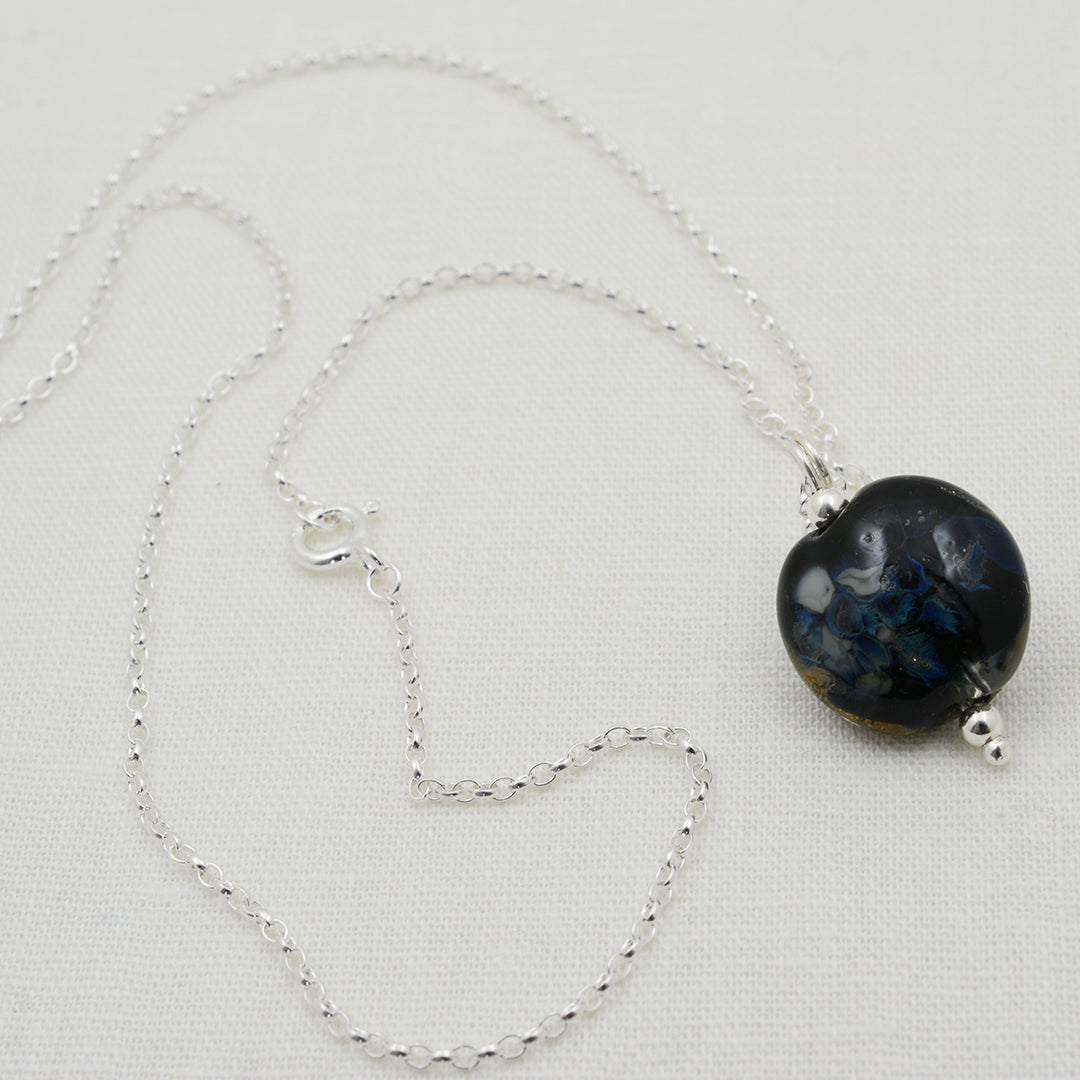 Black and silver lentil shaped glass bead pendant on silver chain