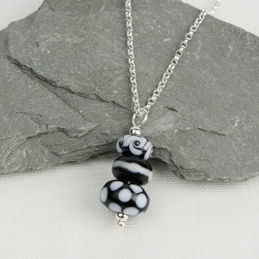 Three black and white glass beads making a pendant on silver chain