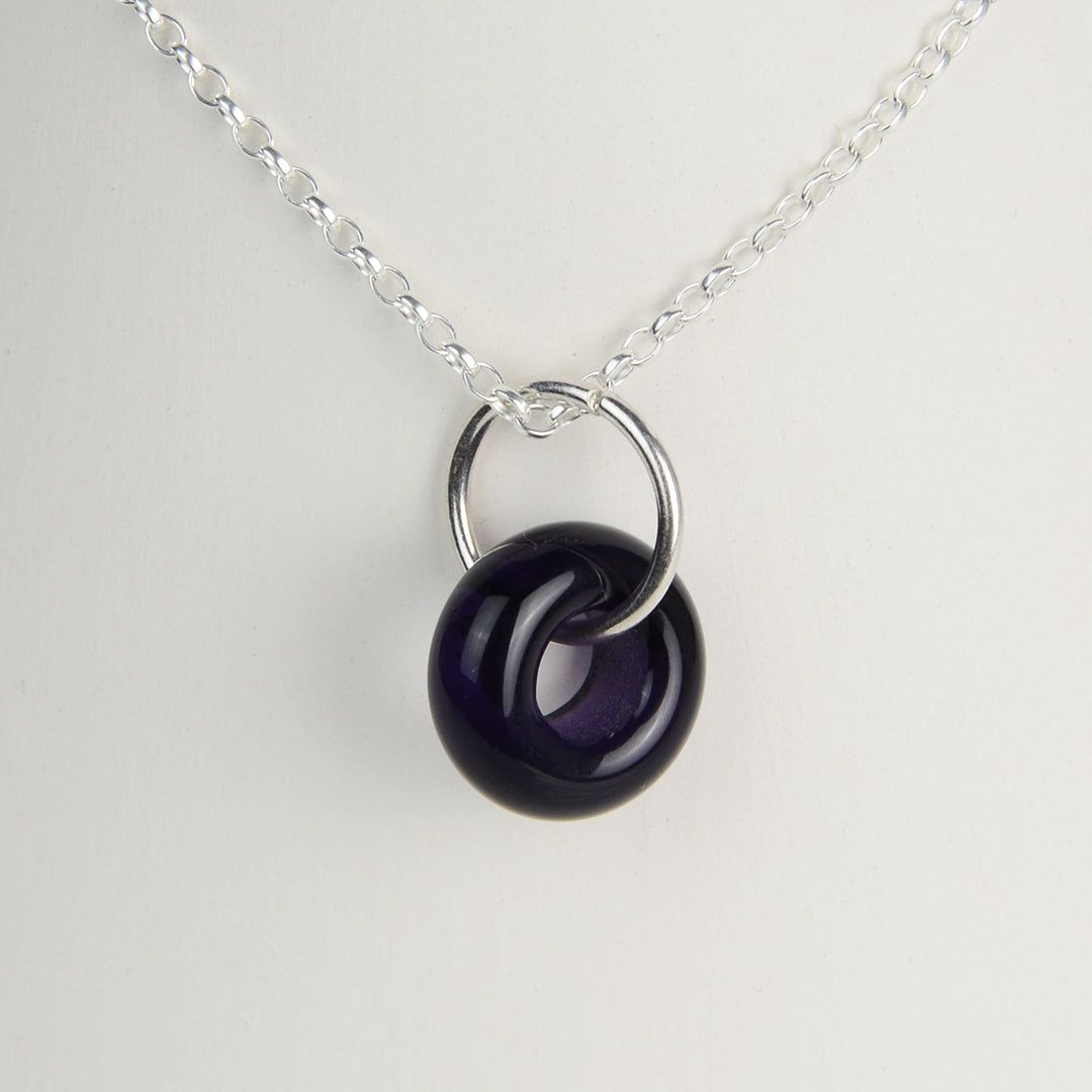 Deep purple glass doughnut shaped bead pendant on silver chain