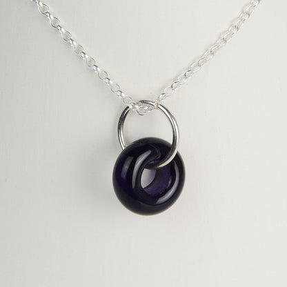 Deep purple glass doughnut shaped bead pendant on silver chain