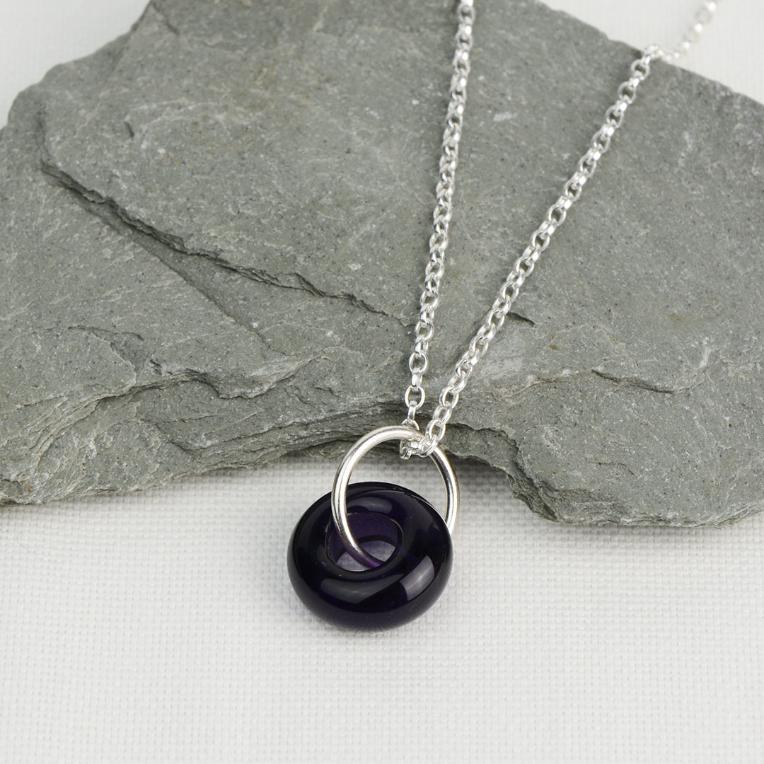 Deep purple glass doughnut shaped bead pendant on silver chain