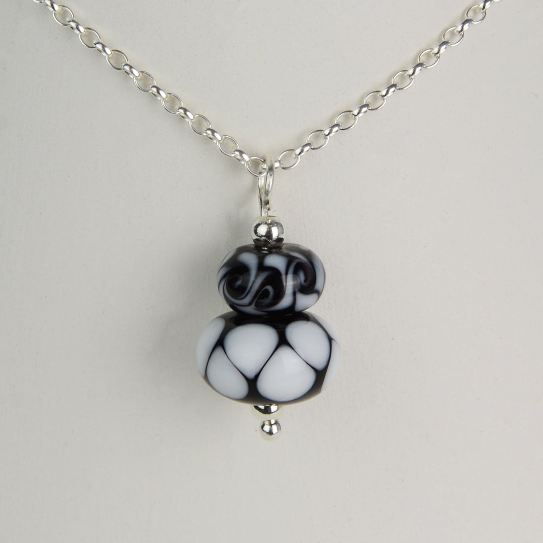 Two black and white glass beads making a pendant on silver chain