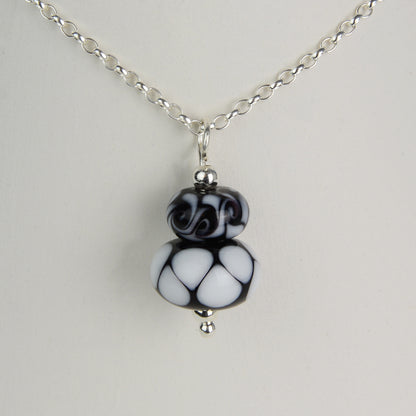 Two black and white glass beads making a pendant on silver chain