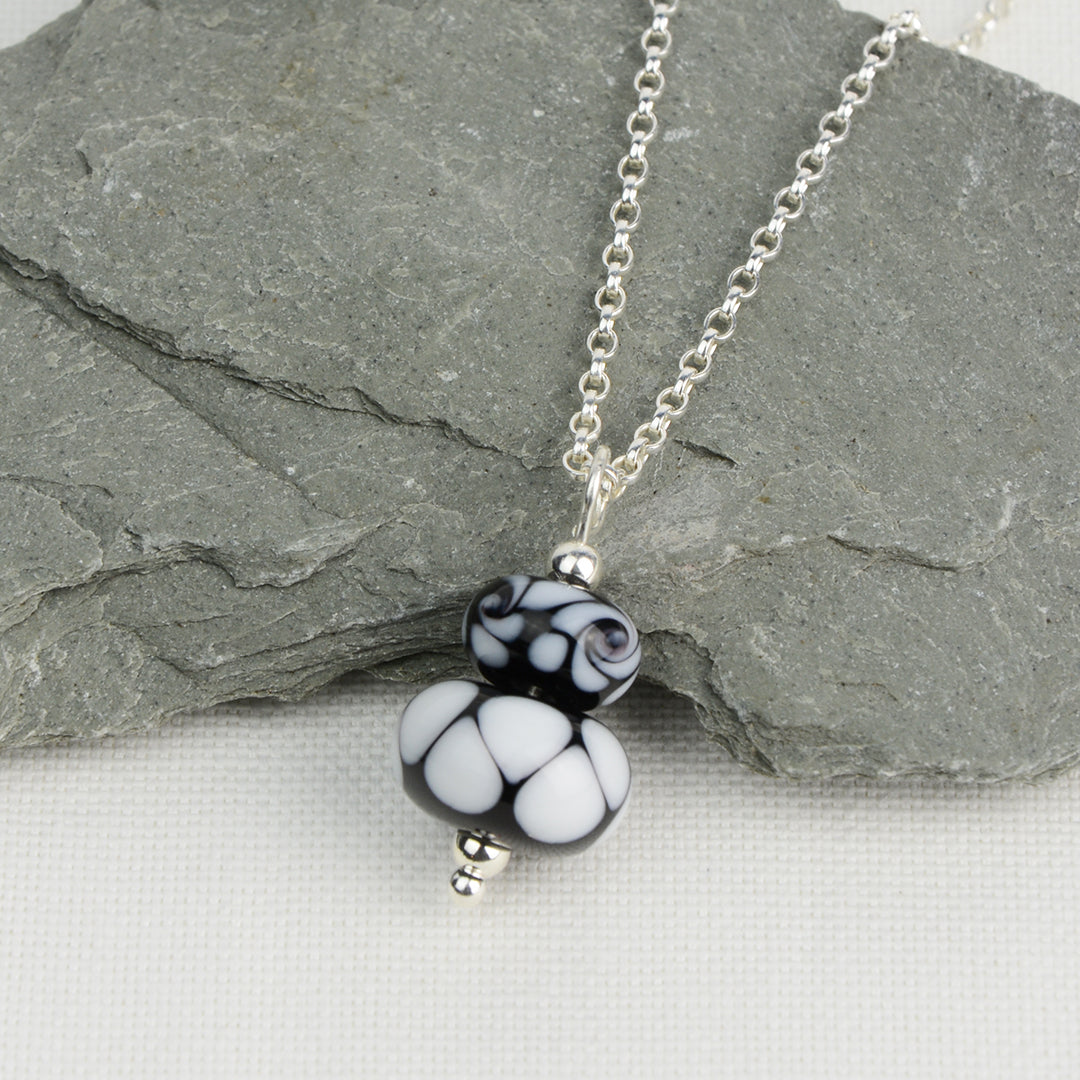 Two black and white glass beads making a pendant on silver chain