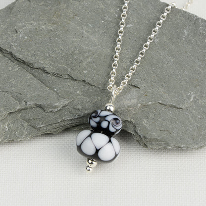 Two black and white glass beads making a pendant on silver chain