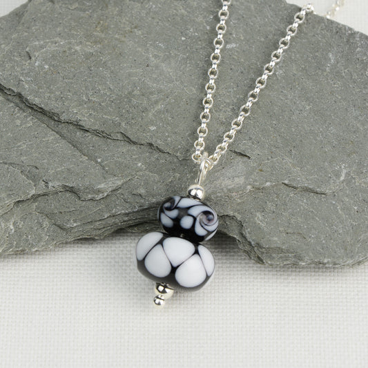 Two black and white glass beads making a pendant on silver chain