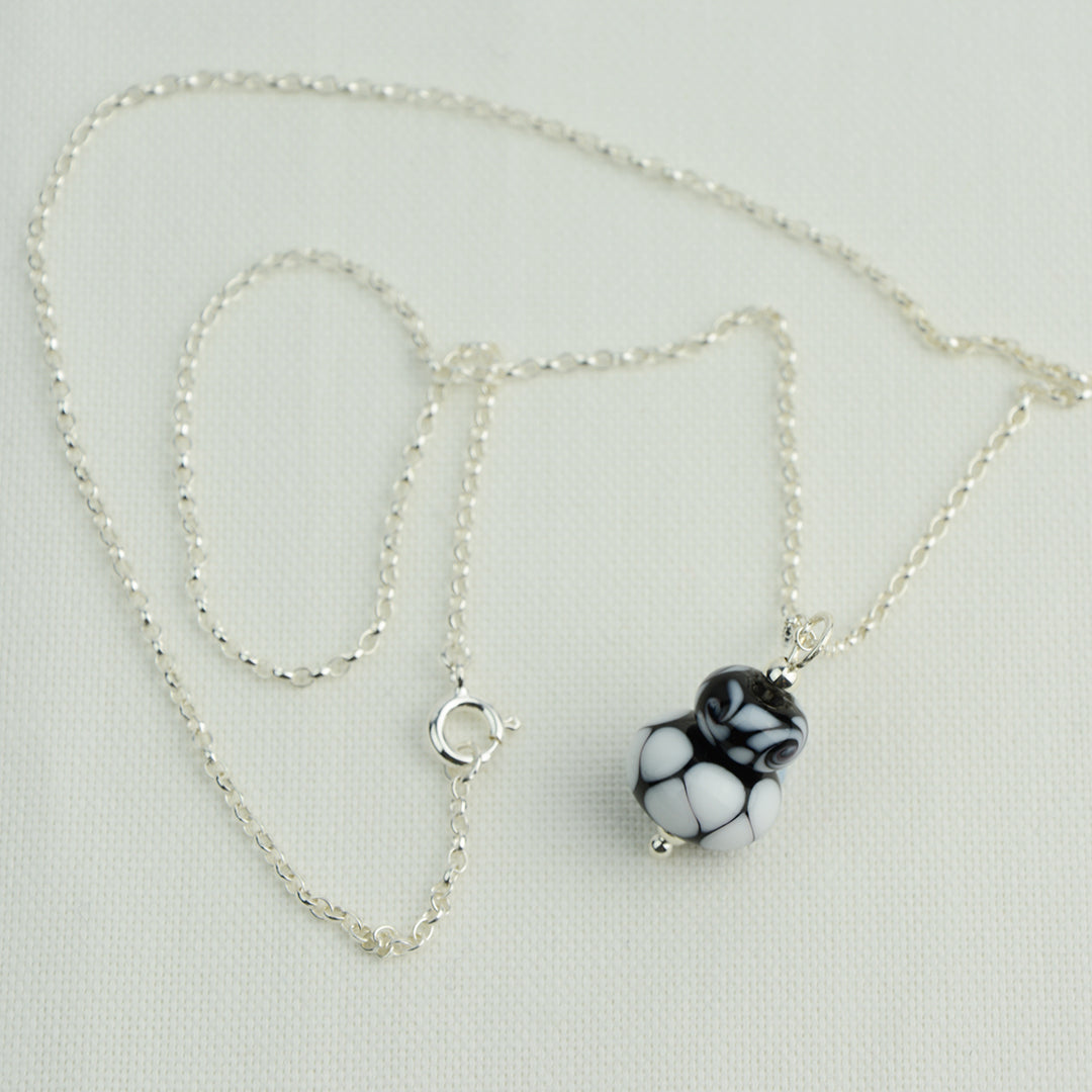 Two black and white glass beads making a pendant on silver chain