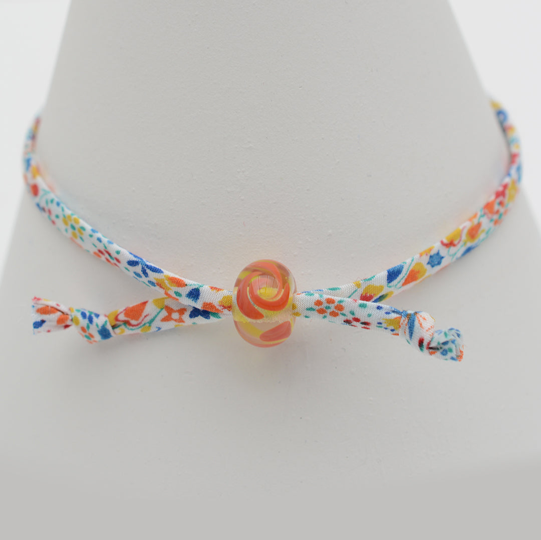 Bracelet made from red, yellow and blue liberty cord with single yellow and orange bead