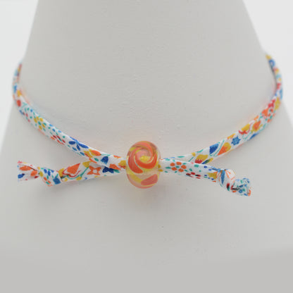 Bracelet made from red, yellow and blue liberty cord with single yellow and orange bead
