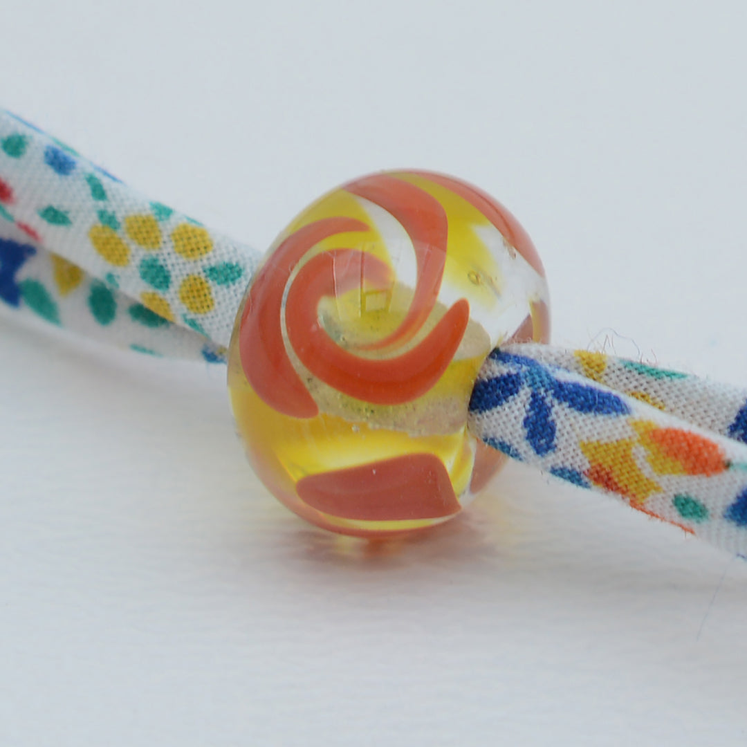 Bracelet made from red, yellow and blue liberty cord with single yellow and orange bead