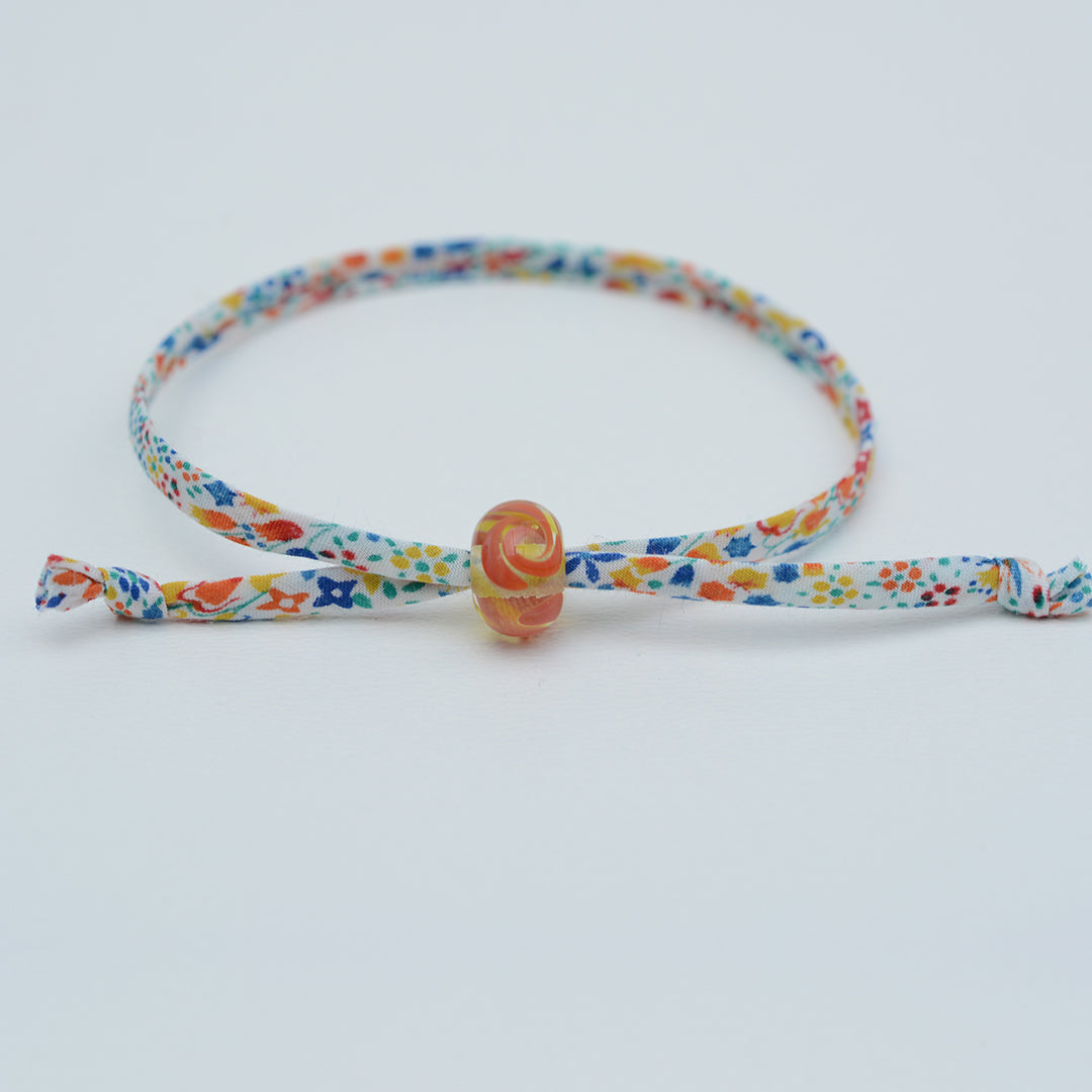 Bracelet made from red, yellow and blue liberty cord with single yellow and orange bead