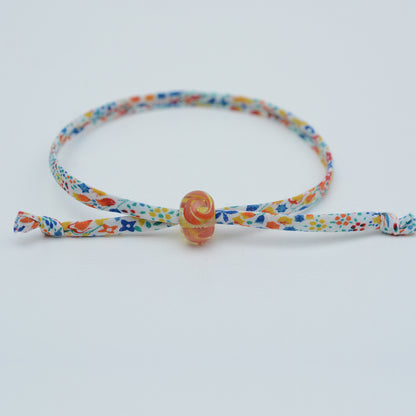 Bracelet made from red, yellow and blue liberty cord with single yellow and orange bead