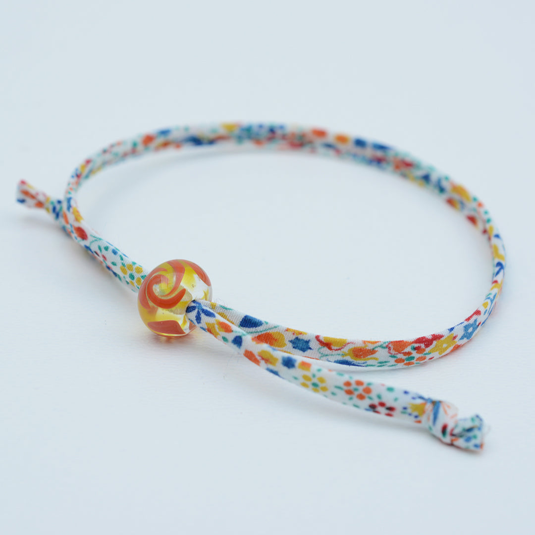 Bracelet made from red, yellow and blue liberty cord with single yellow and orange bead