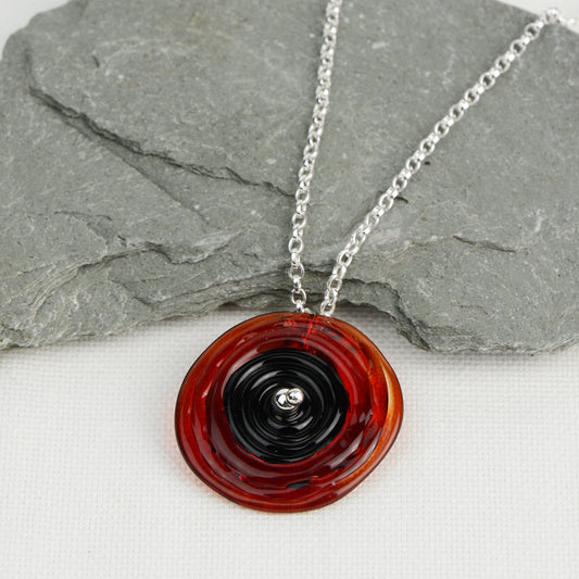 Spiral of red and black glass to replicate a poppy flower on a silver chain