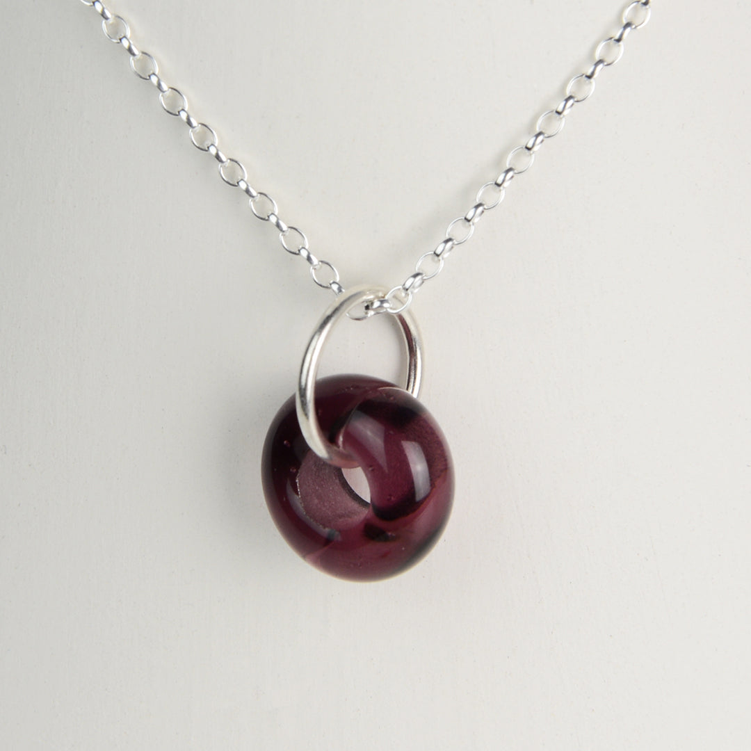 Doughnut shaped plum coloured glass bead on silver chain