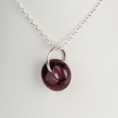 Doughnut shaped plum coloured glass bead on silver chain
