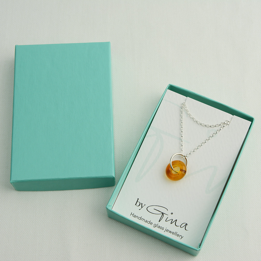 Doughnut shaped amber glass bead on silver chain in turquoise gift box
