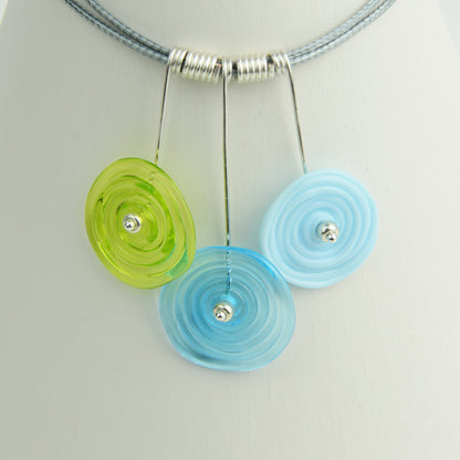 Three spiral beads in lime green, turquoise and pale blueon silver headpin drops with silver spiral spacers on grey necklace cord