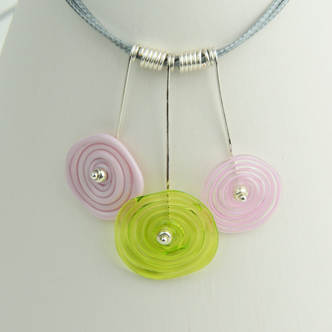 Three spiral beads in baby pink and lime green on silver headpin drops with silver spiral spacers on grey necklace cord