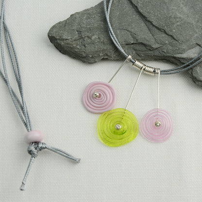 Three spiral beads in baby pink and lime green on silver headpin drops with silver spiral spacers on grey necklace cord