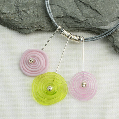 Three spiral beads in baby pink and lime green on silver headpin drops with silver spiral spacers on grey necklace cord